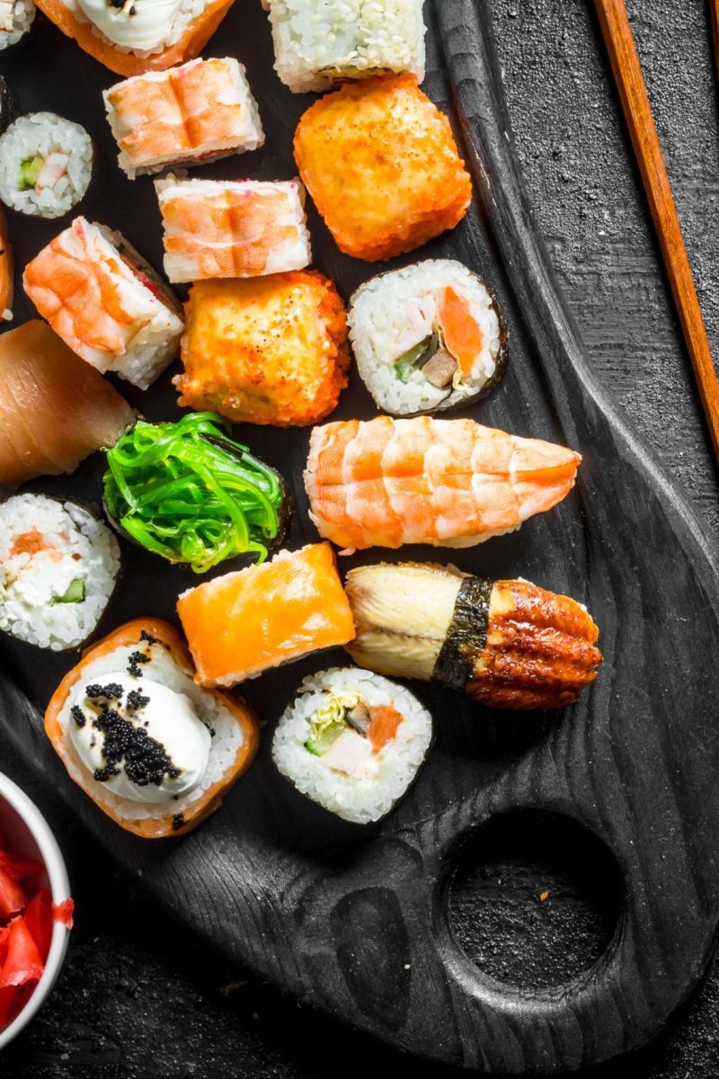 Friske sushi rolls på skærebræt med ingefær og spisepinde hos sushi i Næstved